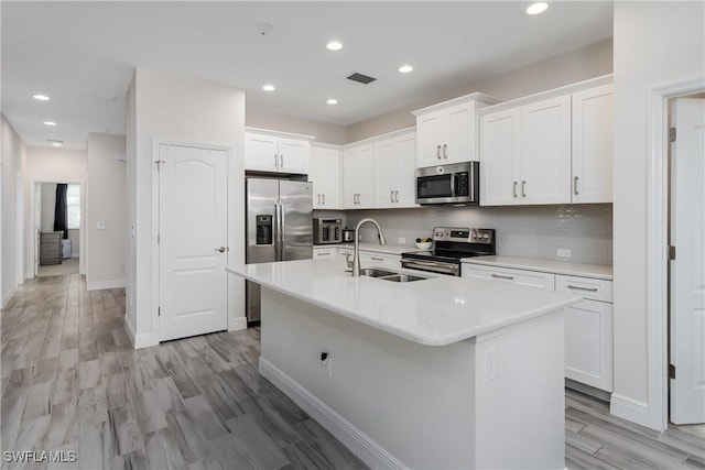 kitchen featuring white cabinetry, sink, a center island with sink, and appliances with stainless steel finishes