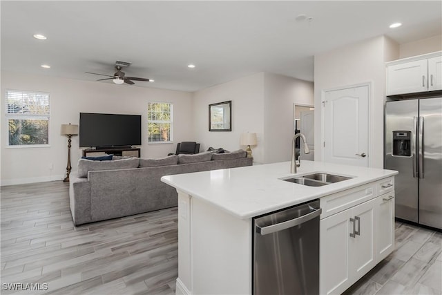 kitchen featuring stainless steel appliances, an island with sink, sink, and white cabinets