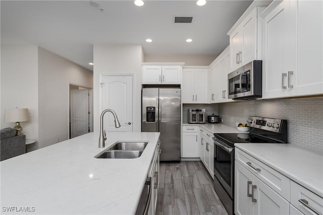 kitchen with white cabinetry, appliances with stainless steel finishes, sink, and decorative backsplash