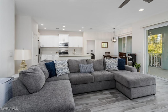 living room featuring ceiling fan with notable chandelier and light wood-type flooring