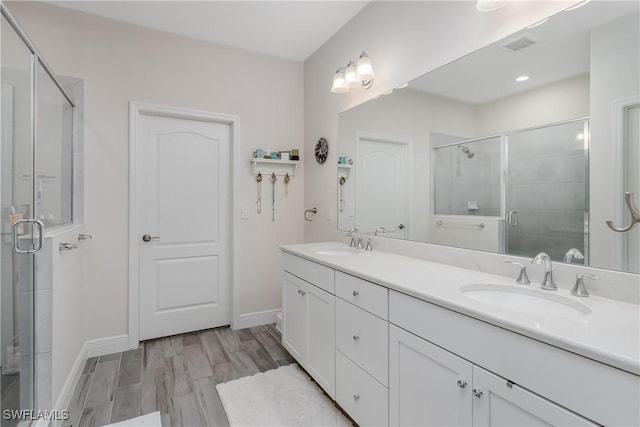 bathroom with hardwood / wood-style flooring, vanity, and a shower with door