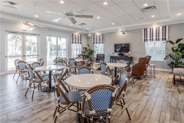 dining area with light hardwood / wood-style flooring, ornamental molding, ceiling fan, a raised ceiling, and french doors