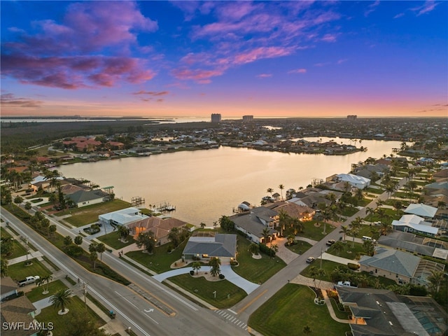 aerial view at dusk featuring a water view