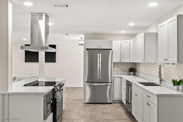 kitchen with sink, island range hood, a textured ceiling, appliances with stainless steel finishes, and white cabinets