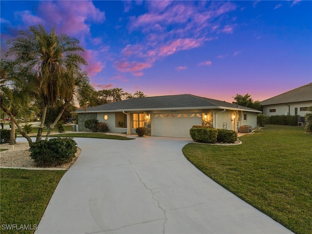 ranch-style home featuring a garage, a yard, and central AC