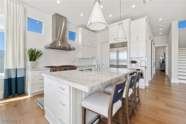 5997 Cypress Ln, Bonita Springs, FL 34134 - kitchen featuring white cabinets, a sink, light wood-style flooring, wall chimney exhaust hood, and stainless steel built in fridge