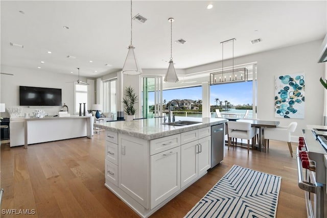 kitchen featuring sink, hanging light fixtures, stainless steel appliances, a kitchen island with sink, and white cabinets