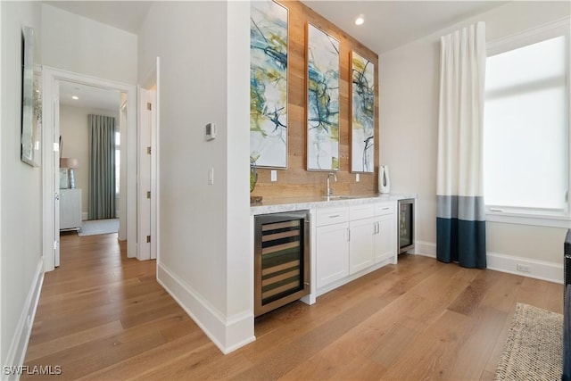 bar with tasteful backsplash, white cabinetry, sink, wine cooler, and light hardwood / wood-style flooring