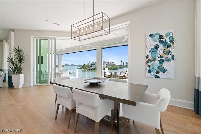 dining space with a water view and light hardwood / wood-style floors