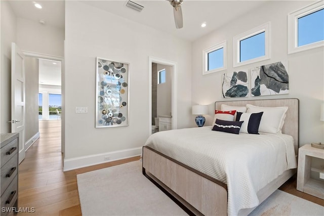 bedroom with connected bathroom, ceiling fan, and light hardwood / wood-style flooring