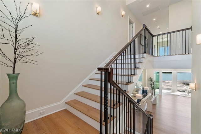 stairway with hardwood / wood-style floors and a high ceiling