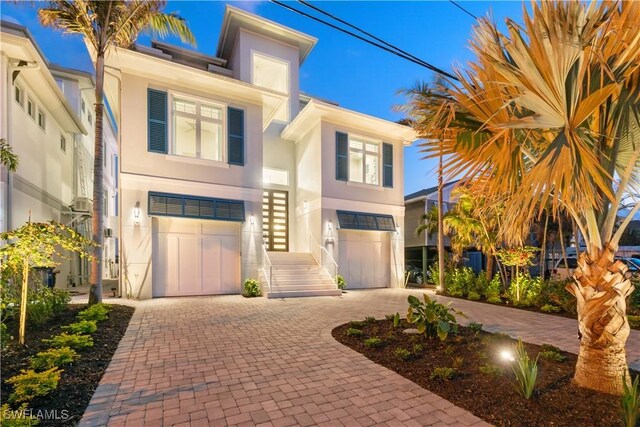 5997 Cypress Ln, Bonita Springs, FL 34134 - view of front facade with decorative driveway, an attached garage, and stucco siding