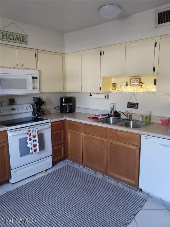 kitchen with light tile patterned flooring, sink, and white appliances