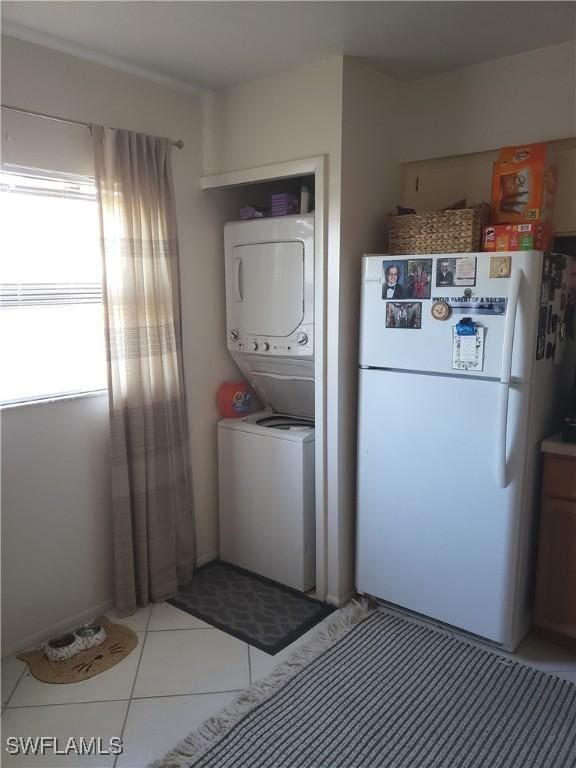 laundry room featuring stacked washer / drying machine and light tile patterned floors