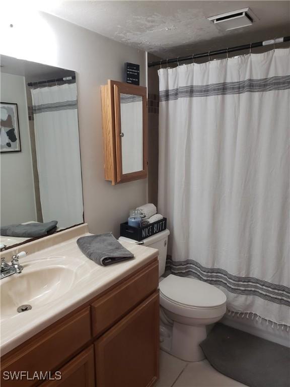 bathroom with vanity, a textured ceiling, tile patterned floors, and toilet