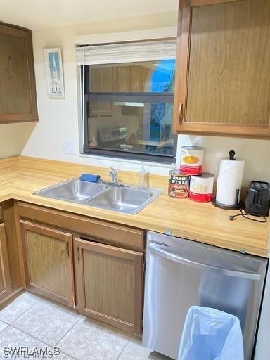 kitchen with sink, light tile patterned floors, and stainless steel dishwasher