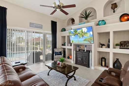 living room with a towering ceiling, built in features, and ceiling fan