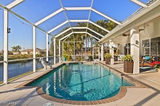 view of pool with a lanai, a patio, and a water view