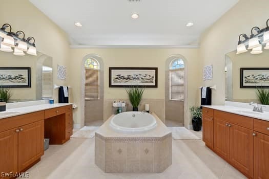 bathroom with vanity, a wealth of natural light, tile patterned floors, and a relaxing tiled tub