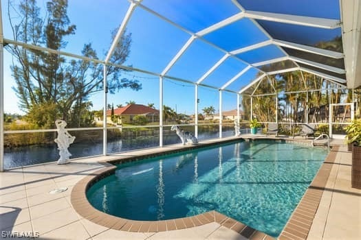 view of pool with a water view, glass enclosure, and a patio area