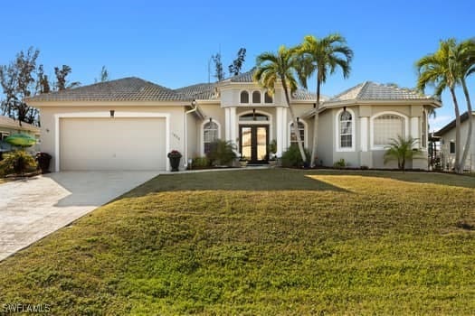 mediterranean / spanish-style home with french doors, a garage, and a front lawn