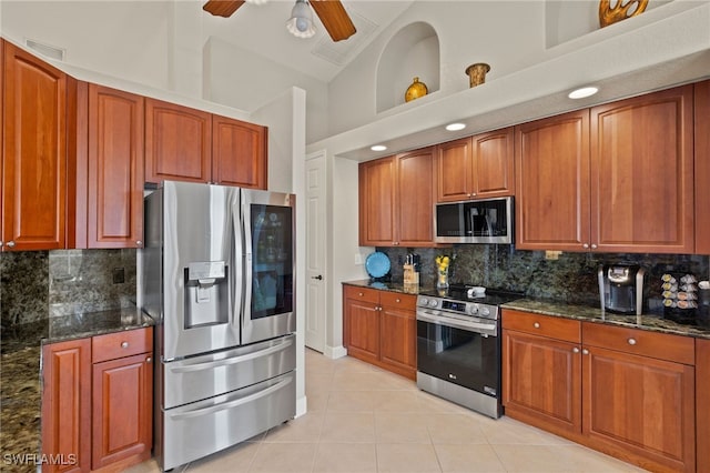 kitchen featuring tasteful backsplash, stainless steel appliances, light tile patterned floors, and dark stone countertops