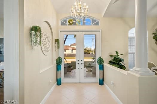 doorway featuring light tile patterned flooring, decorative columns, lofted ceiling, a notable chandelier, and french doors