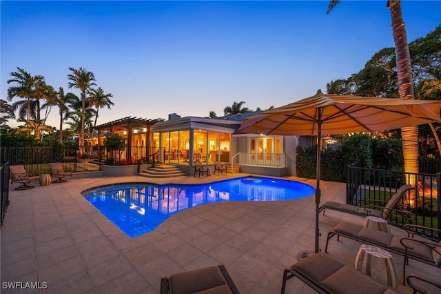 pool at dusk featuring a patio and a pergola