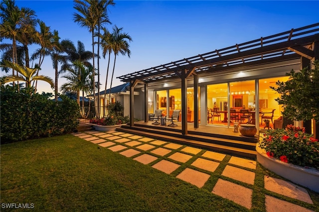 back house at dusk with a patio, a pergola, and a yard