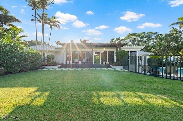 rear view of property featuring a yard, a patio, and a fenced in pool