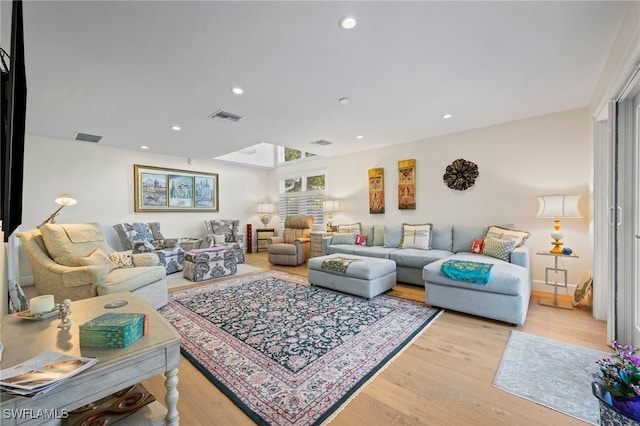 living room featuring light hardwood / wood-style flooring and a skylight