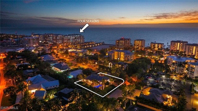 aerial view at dusk featuring a water view