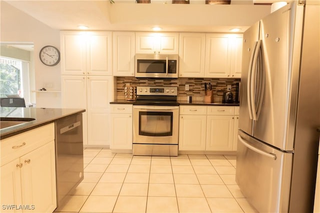 kitchen featuring stainless steel appliances, light tile patterned flooring, white cabinets, and decorative backsplash