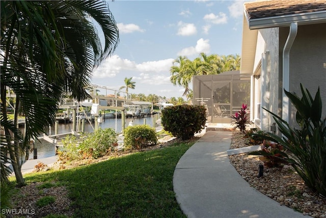 view of yard with a water view, a dock, and a lanai