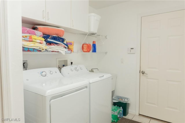 laundry area with independent washer and dryer, light tile patterned floors, and cabinets