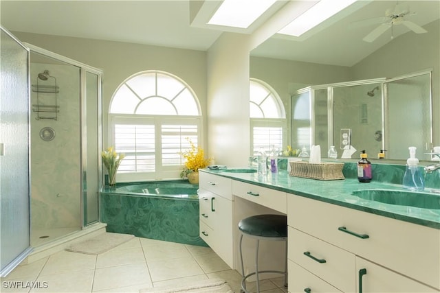 bathroom featuring shower with separate bathtub, vaulted ceiling with skylight, vanity, ceiling fan, and tile patterned floors