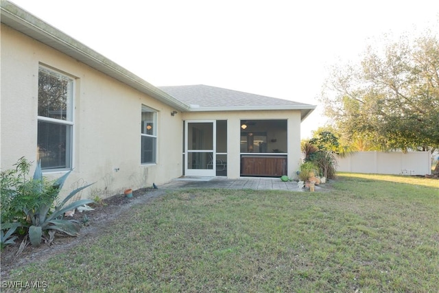 rear view of property featuring a sunroom and a lawn