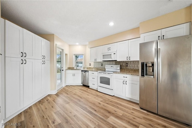 kitchen featuring stainless steel appliances, tasteful backsplash, light wood-style flooring, and white cabinets