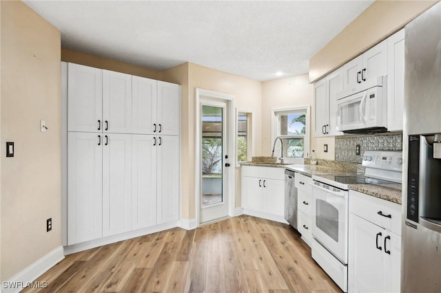 kitchen featuring white cabinets, stone counters, appliances with stainless steel finishes, and light wood finished floors