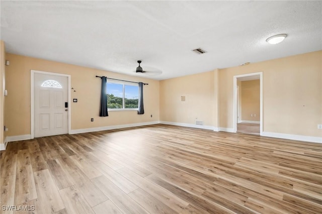 unfurnished living room featuring light wood-style floors, ceiling fan, visible vents, and baseboards