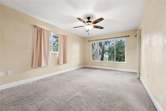 carpeted spare room featuring ceiling fan, a textured ceiling, and baseboards