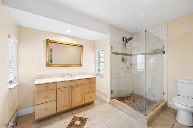 bathroom with tile patterned flooring, toilet, vanity, baseboards, and a shower stall