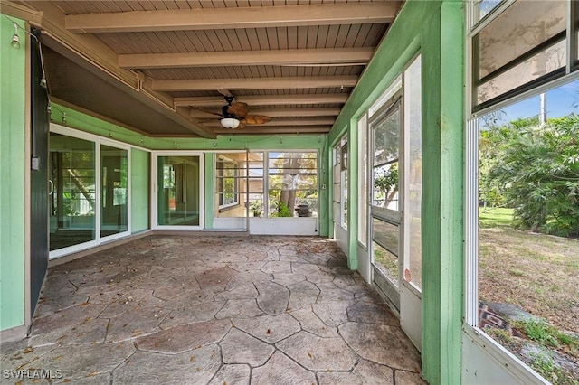 unfurnished sunroom with a wealth of natural light, beam ceiling, and a ceiling fan