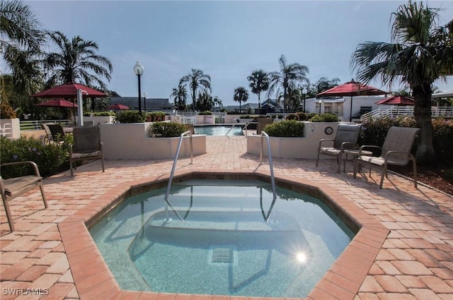 community pool with a community hot tub, a patio, and fence