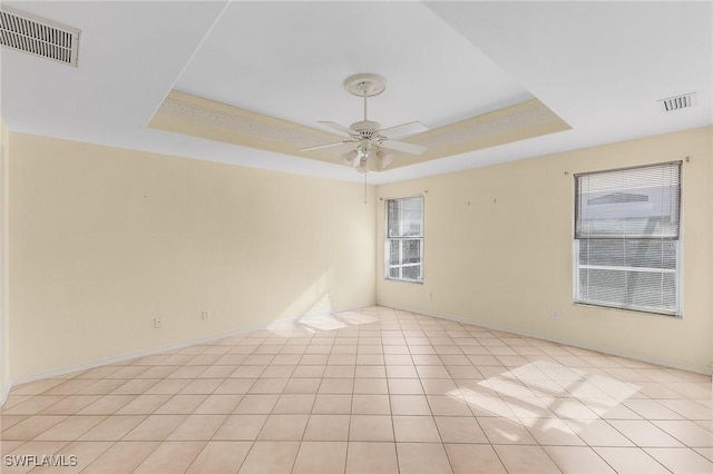 unfurnished room featuring a ceiling fan, a raised ceiling, visible vents, and light tile patterned floors