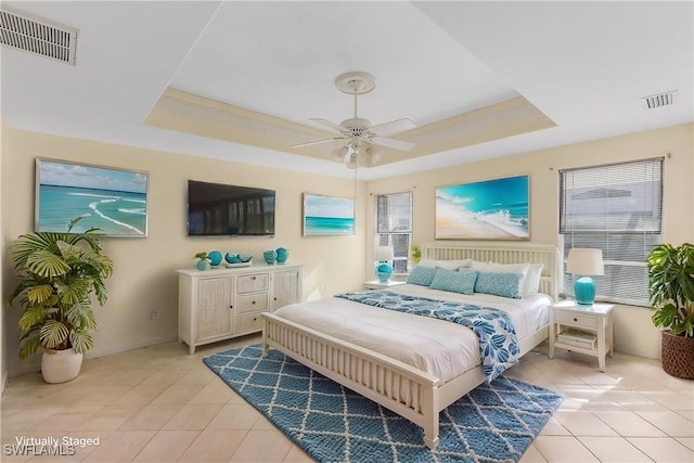 bedroom featuring ceiling fan, a raised ceiling, and light tile patterned floors