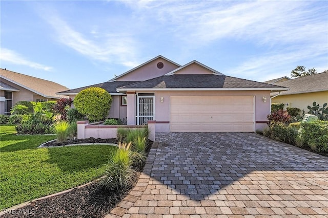 ranch-style home with decorative driveway, an attached garage, a front yard, and stucco siding