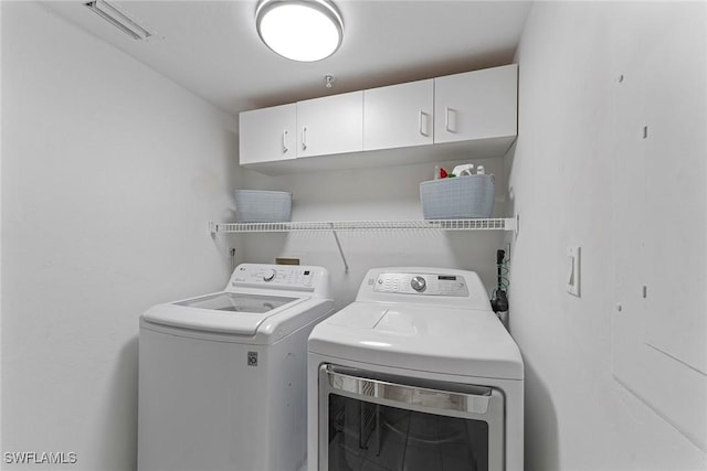 clothes washing area featuring cabinets and separate washer and dryer