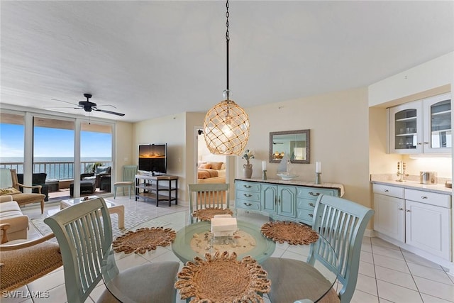 tiled dining room featuring expansive windows and ceiling fan