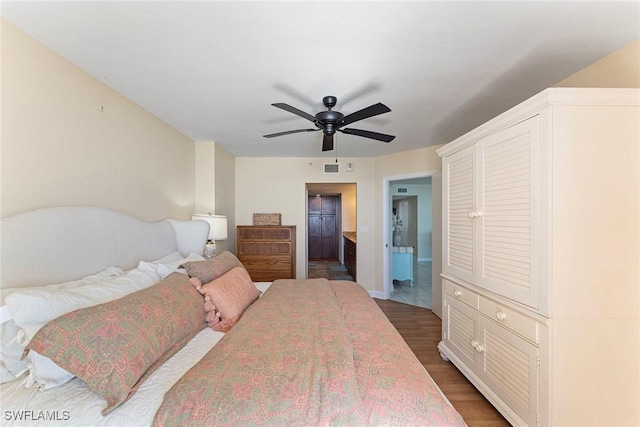 bedroom featuring ceiling fan, ensuite bath, and dark hardwood / wood-style floors